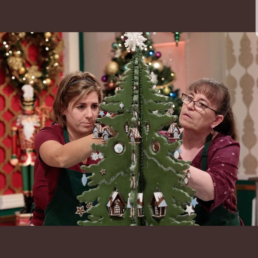 A photo of Gisella and Beatriz working on a green gingerbread Christmas Tree on the set of Holiday Gingerbread Showdown.